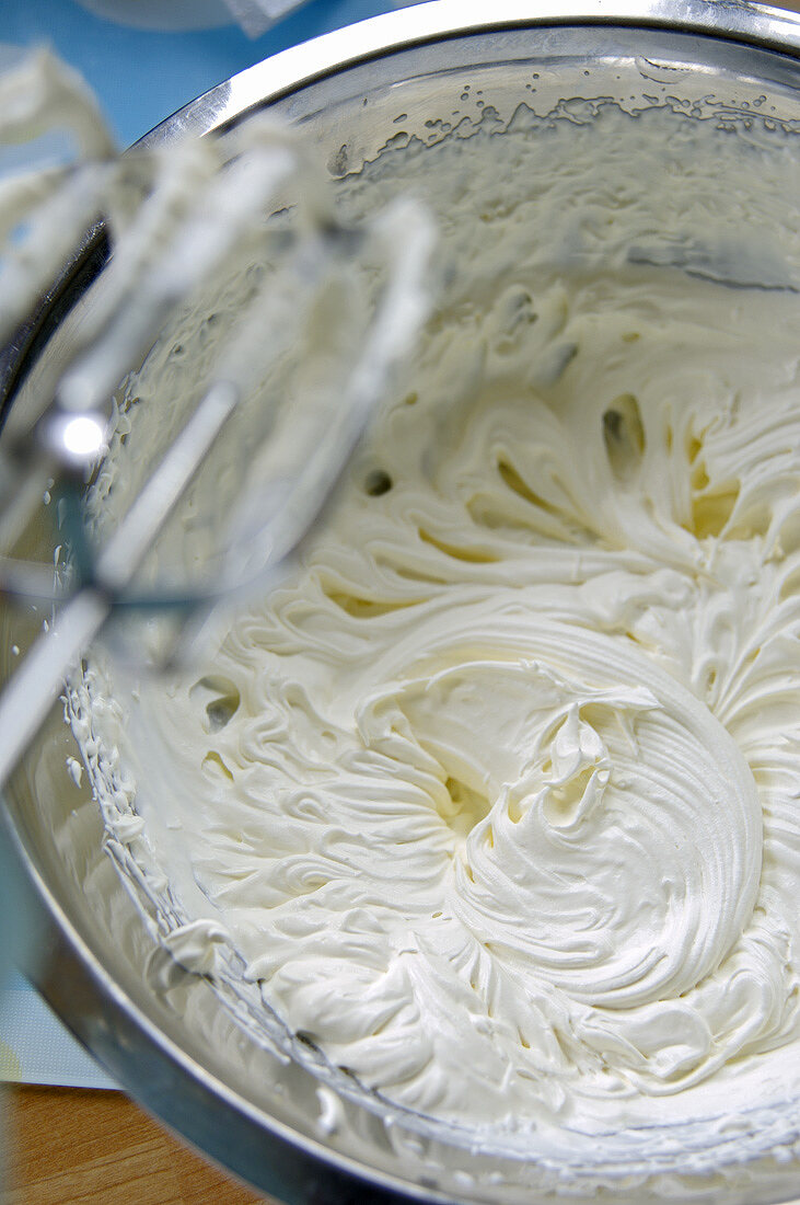 Sahne in einer Schüssel mit einem Mixer geschlagen