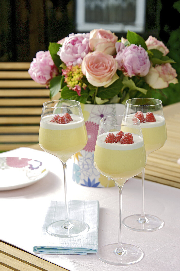 Three glasses of lemon mousse with raspberries out of doors