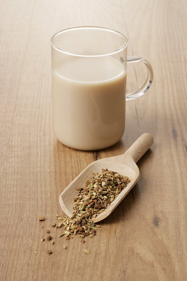 A glass cup of Yogi tea with aniseed in a wooden scoop