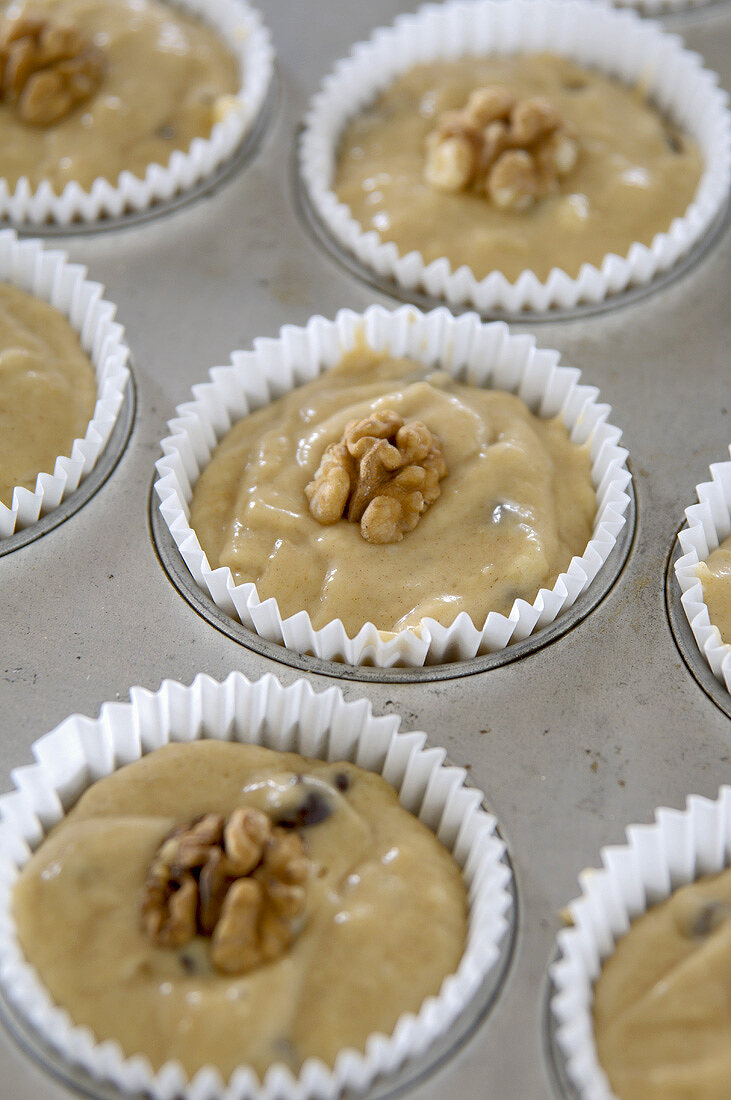 Bananen-Schokoladenteig im Muffinblech mit Walnüssen belegt