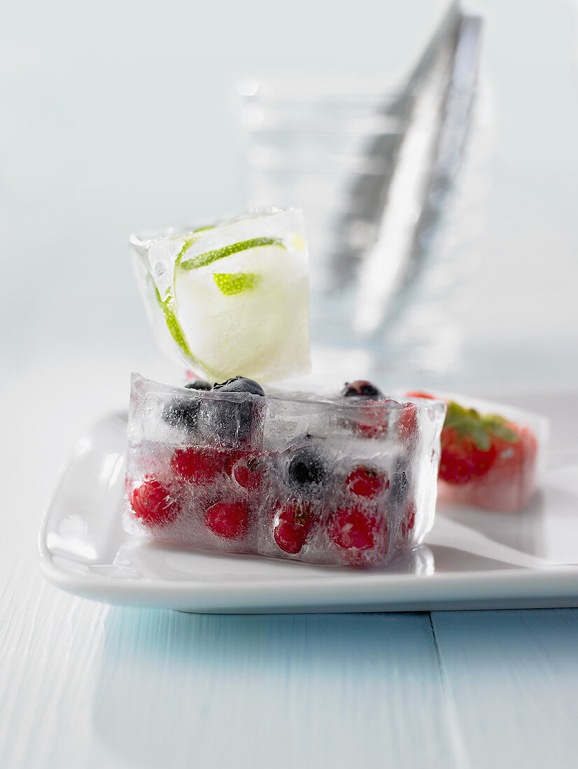 Eiswürfel mit gefrorenen Beeren und Limettenzesten