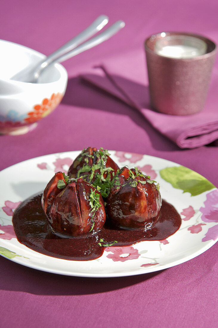 Drei in Rotwein-Brombeersauce pochierte Feigen