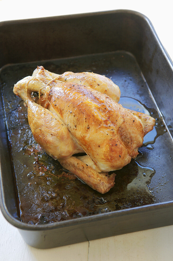 Whole, roast chicken in a roasting tin