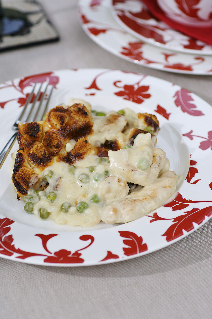 Hähnchen-Gratin mit Erbsen und Croûtons auf einem Teller