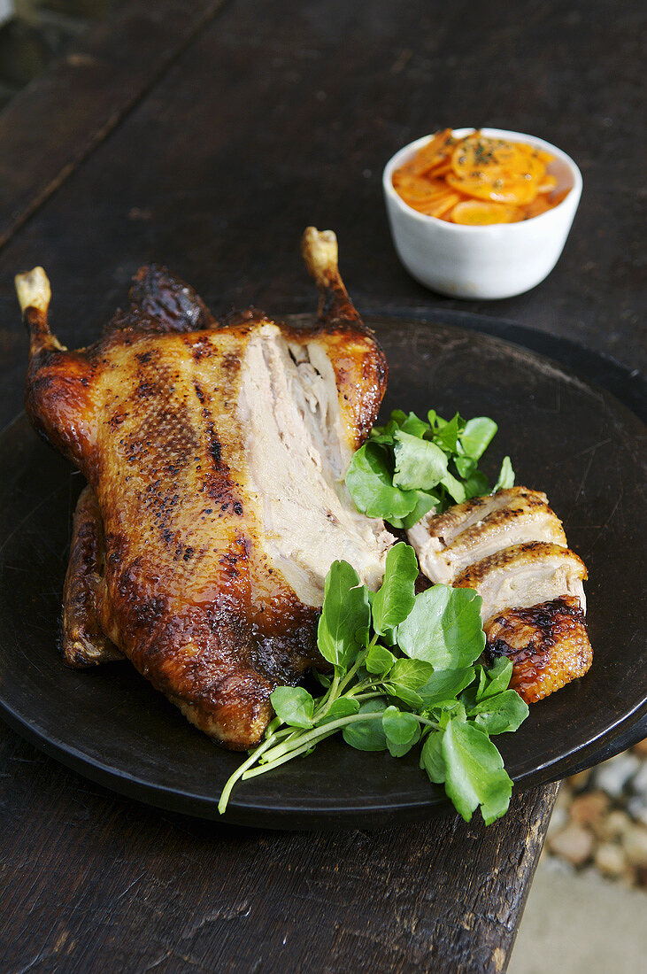 Honey-glazed duck, partly carved, with carrots