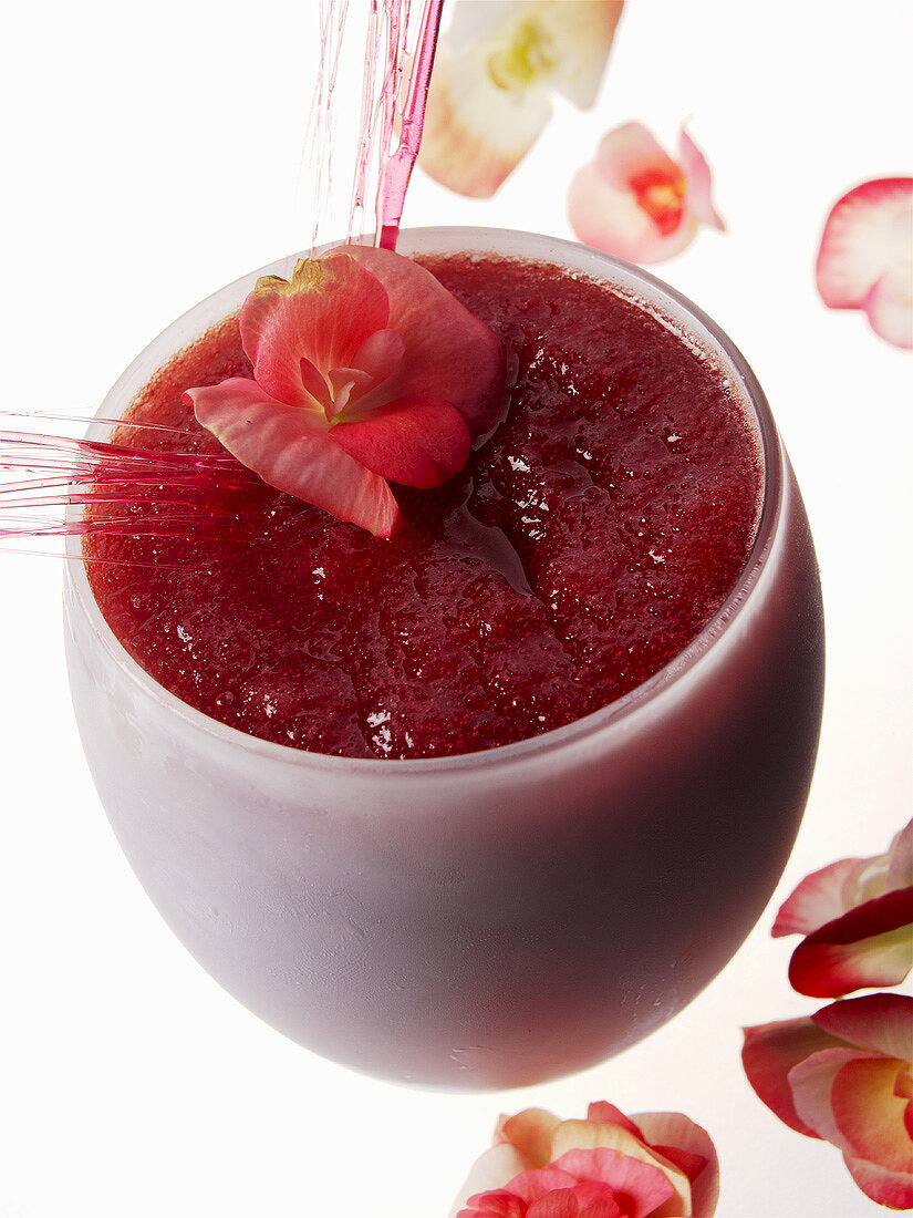 Einr roter Frucht-Cocktail mit Blüten und Karamellgitter