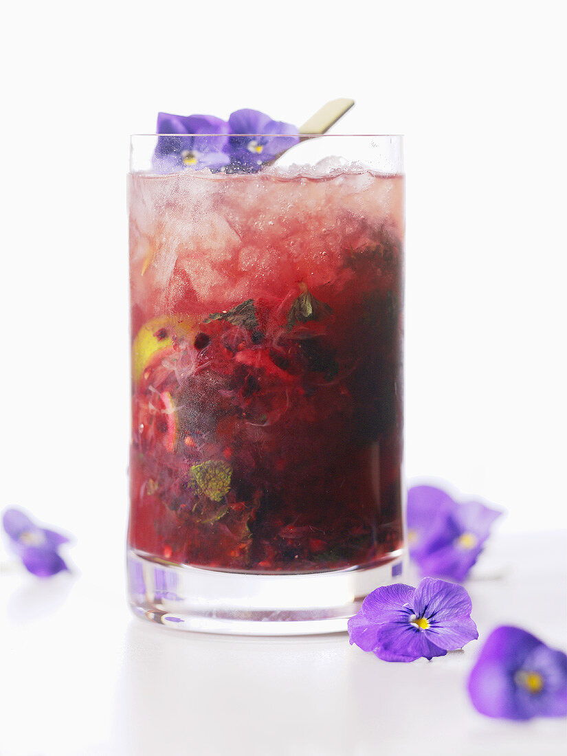 A glass of berry cocktail with flowers