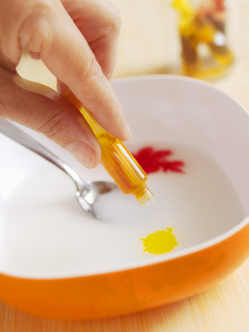 Adding drops of orange flavouring to icing