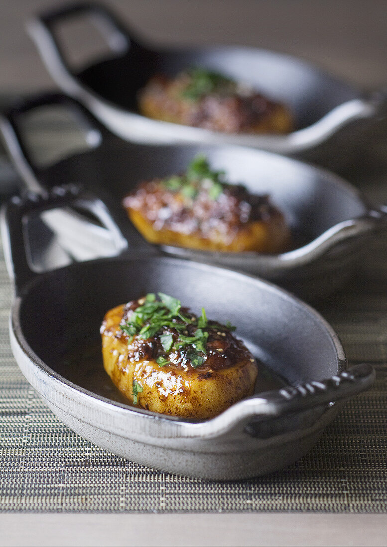 Three stuffed baked potatoes in cast-iron cookware