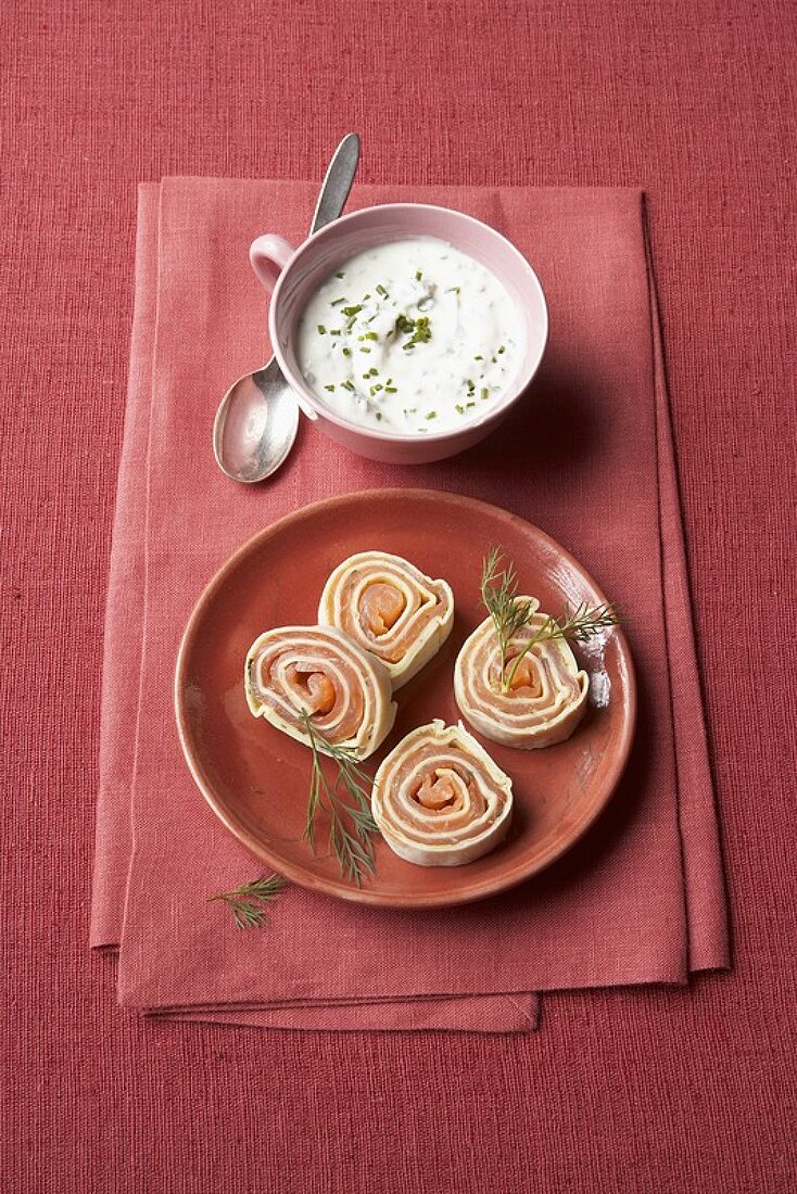Four slices of smoked salmon roulade with herb sour cream