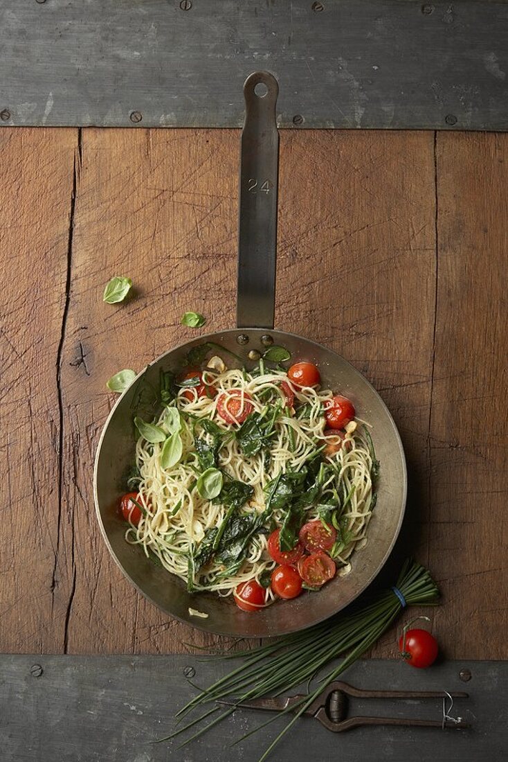 Pan of capellini with spinach, cocktail tomatoes and herbs