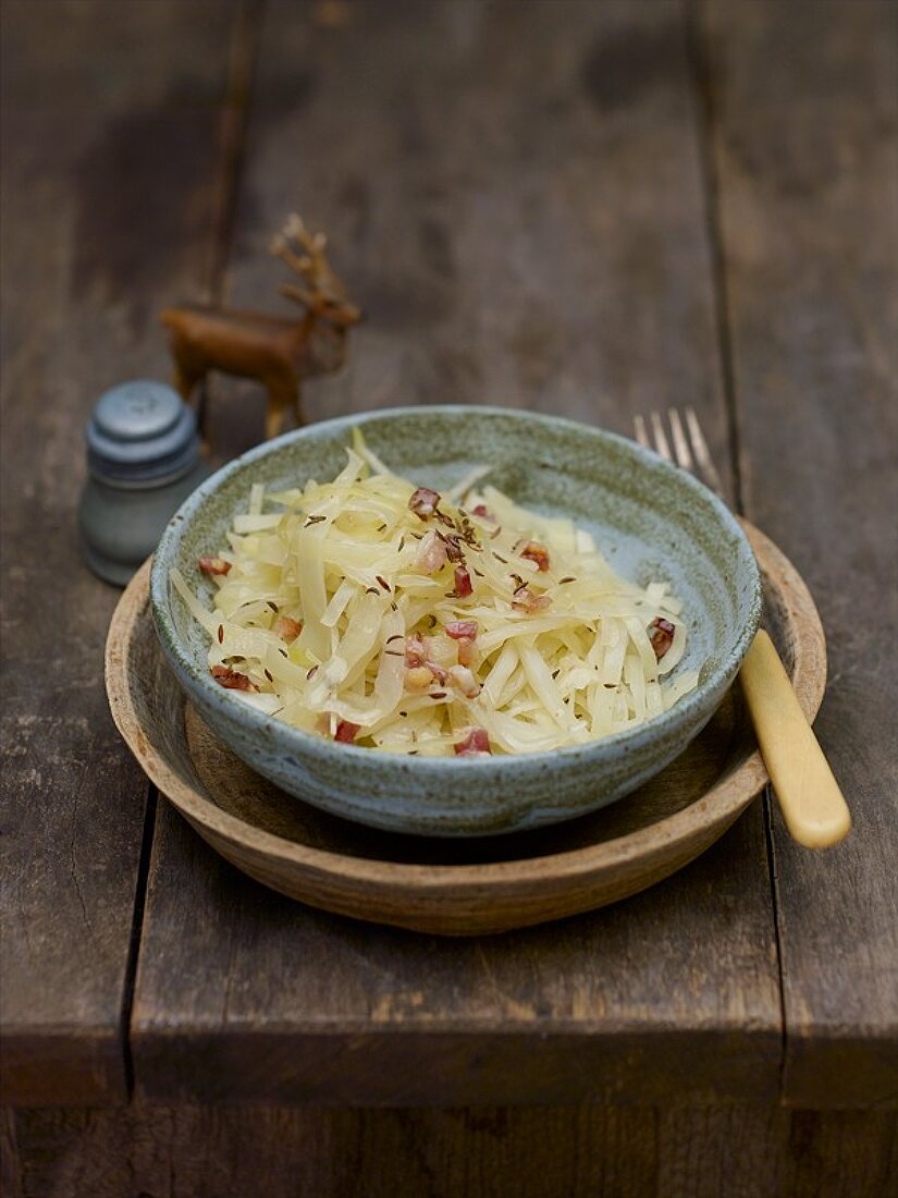 Cabbage salad with caraway seeds and bacon in pottery bowl