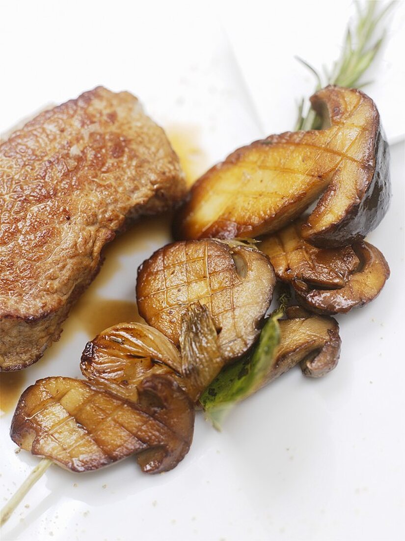 Grilled veal steak with mushrooms on rosemary skewer