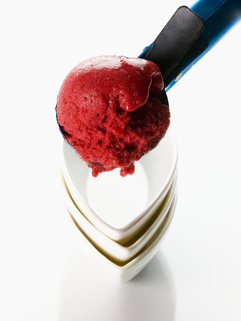 A scoop of raspberry ice cream in an ice cream scoop