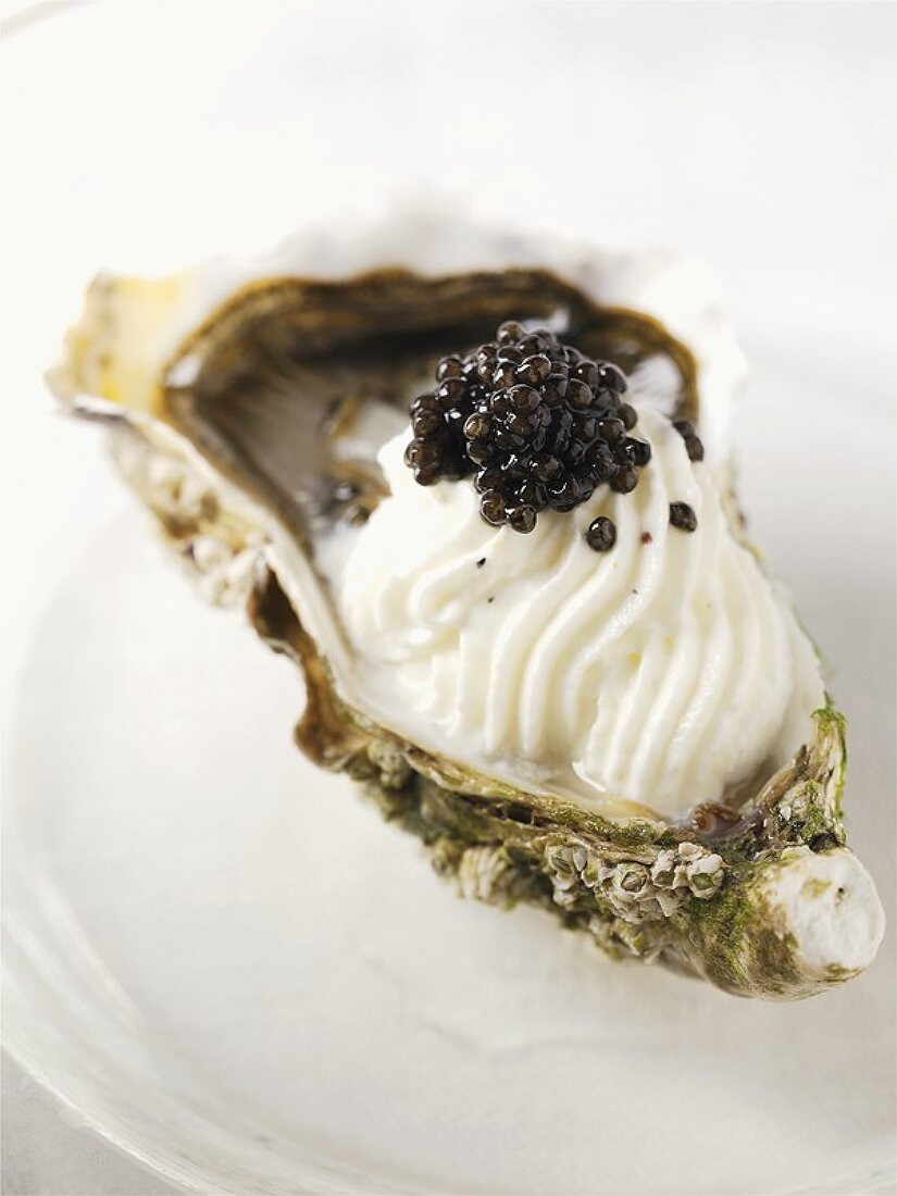 An oyster with whipped cream and caviar