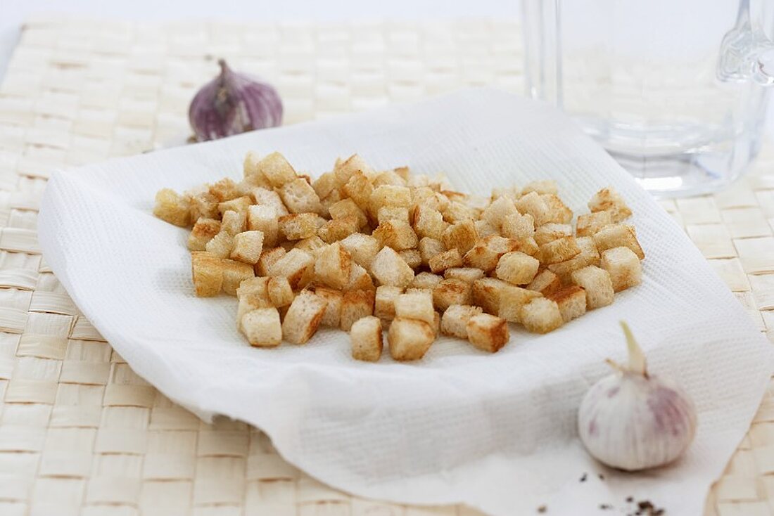 Croutons on kitchen paper with garlic bulbs