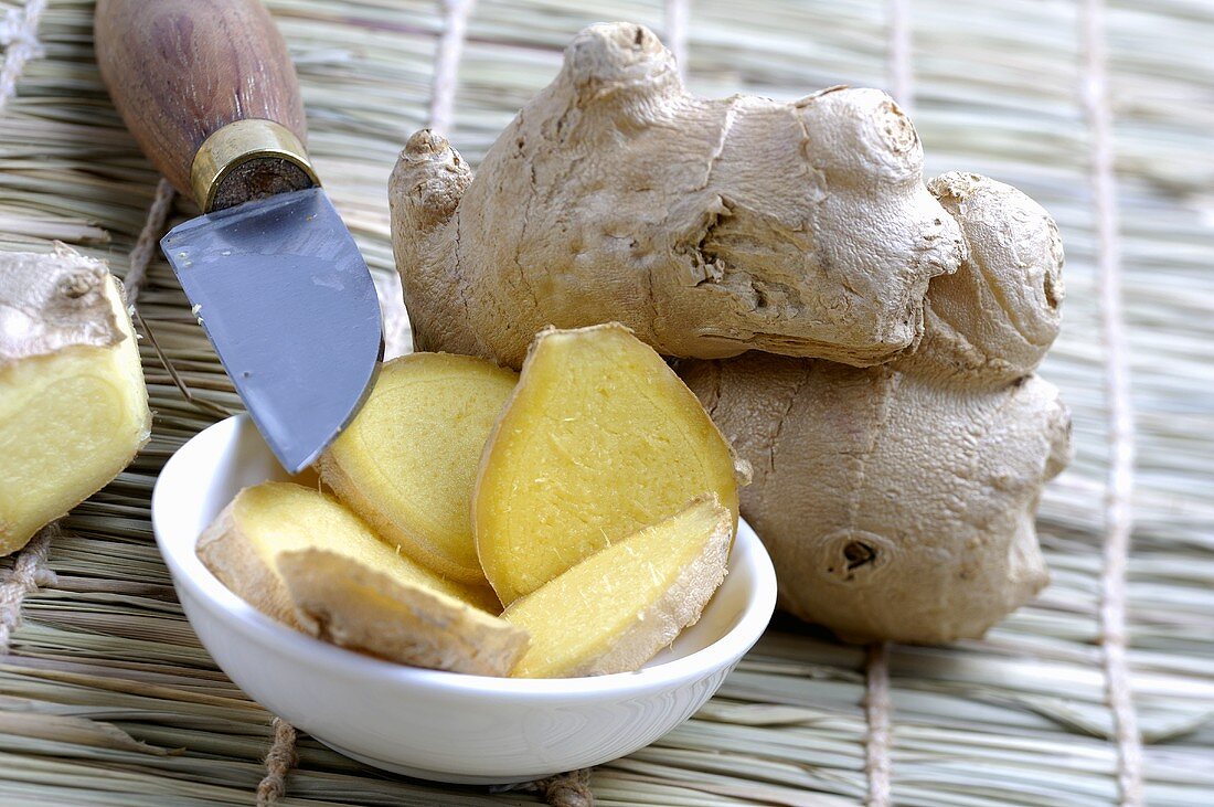 Ginger root, whole and sliced, with a knife