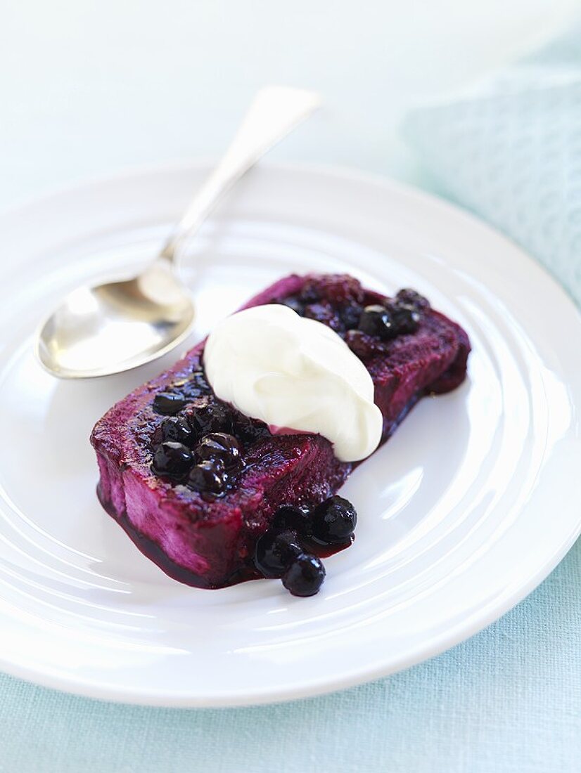 A slice of summer pudding with blueberry sauce