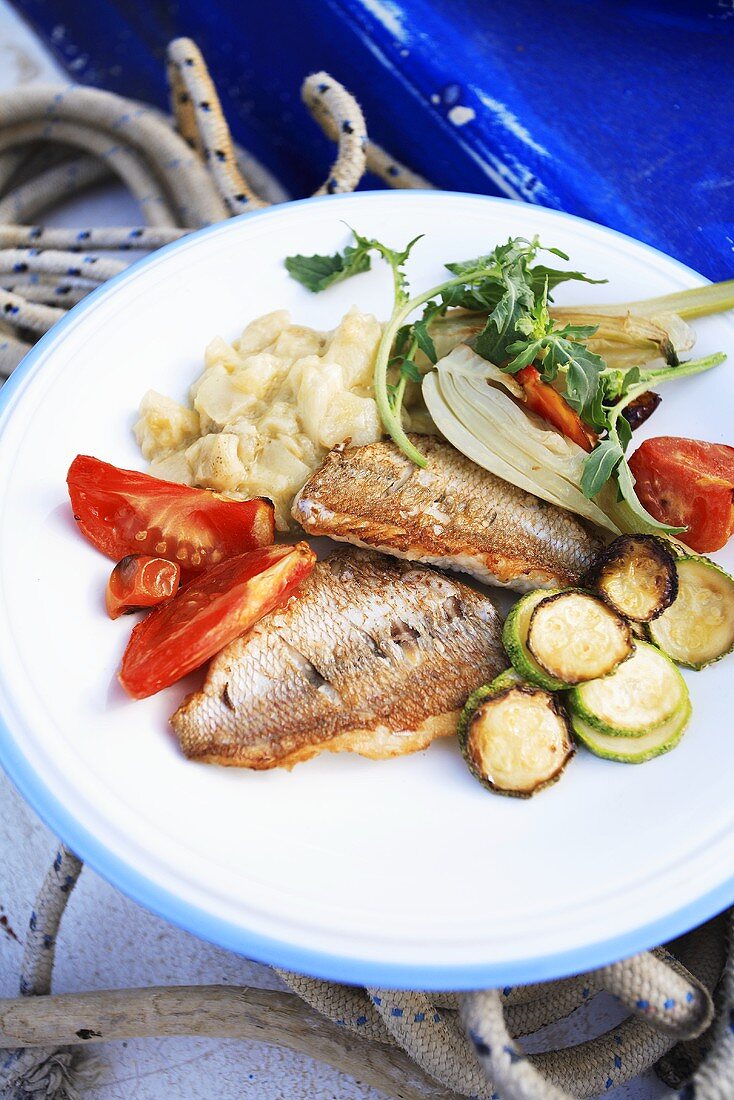 Fried red mullet fillets with vegetables in a boat