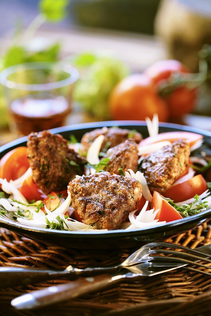 Grilled meat patties on tomato and onion salad
