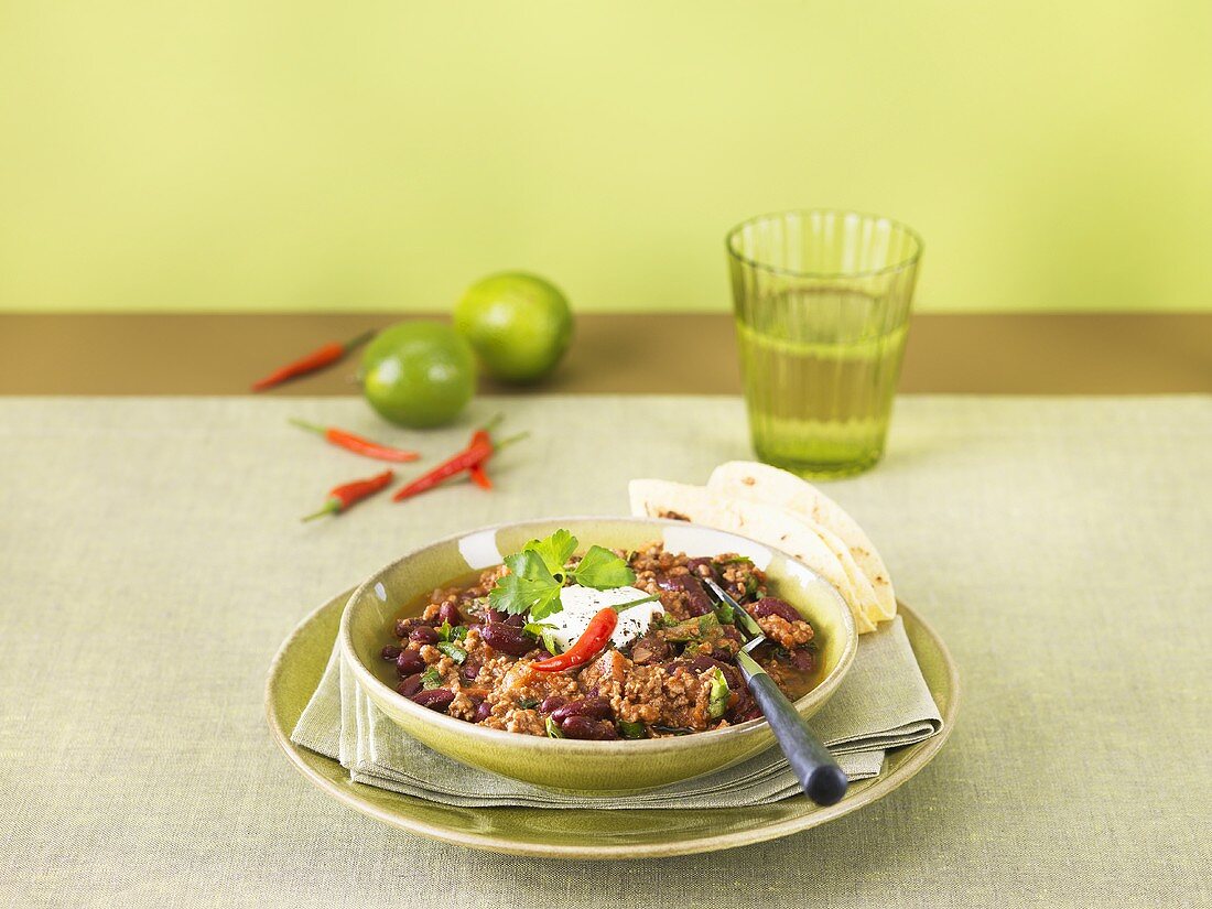 A plate of chili con carne with tortilla