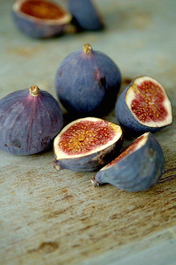 Whole and halved figs on wooden background