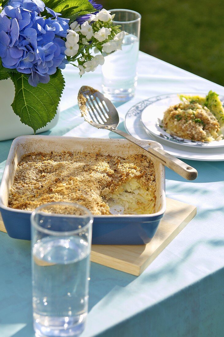 Potato and anchovy gratin in baking dish and on plate