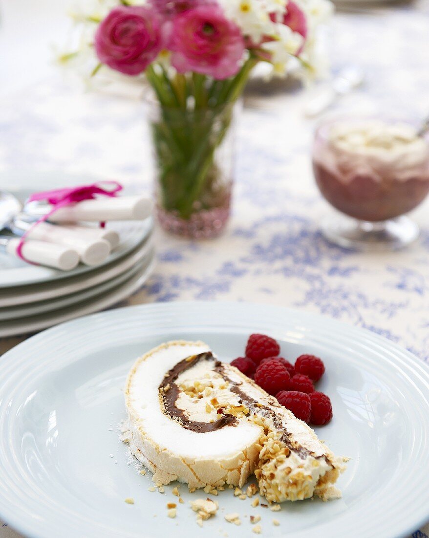 A piece of meringue roulade with cream & nut filling & raspberries