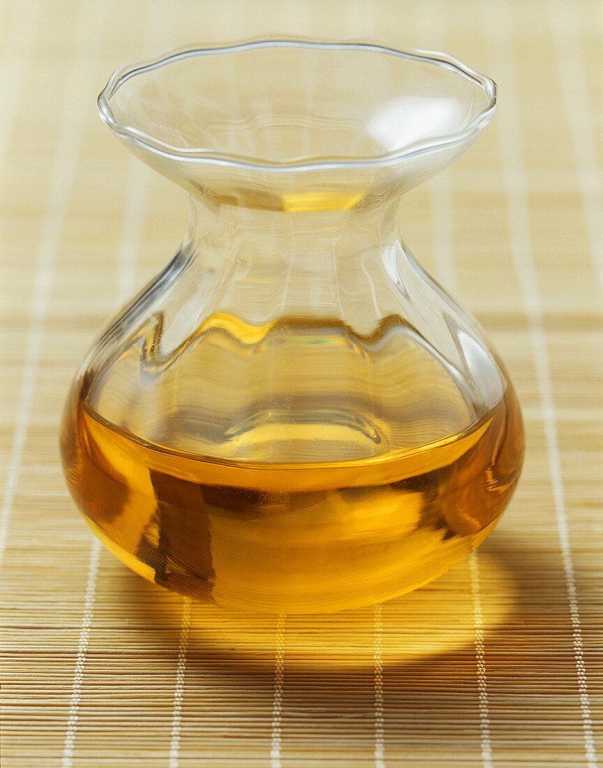 Groundnut oil in a glass carafe on a bamboo mat
