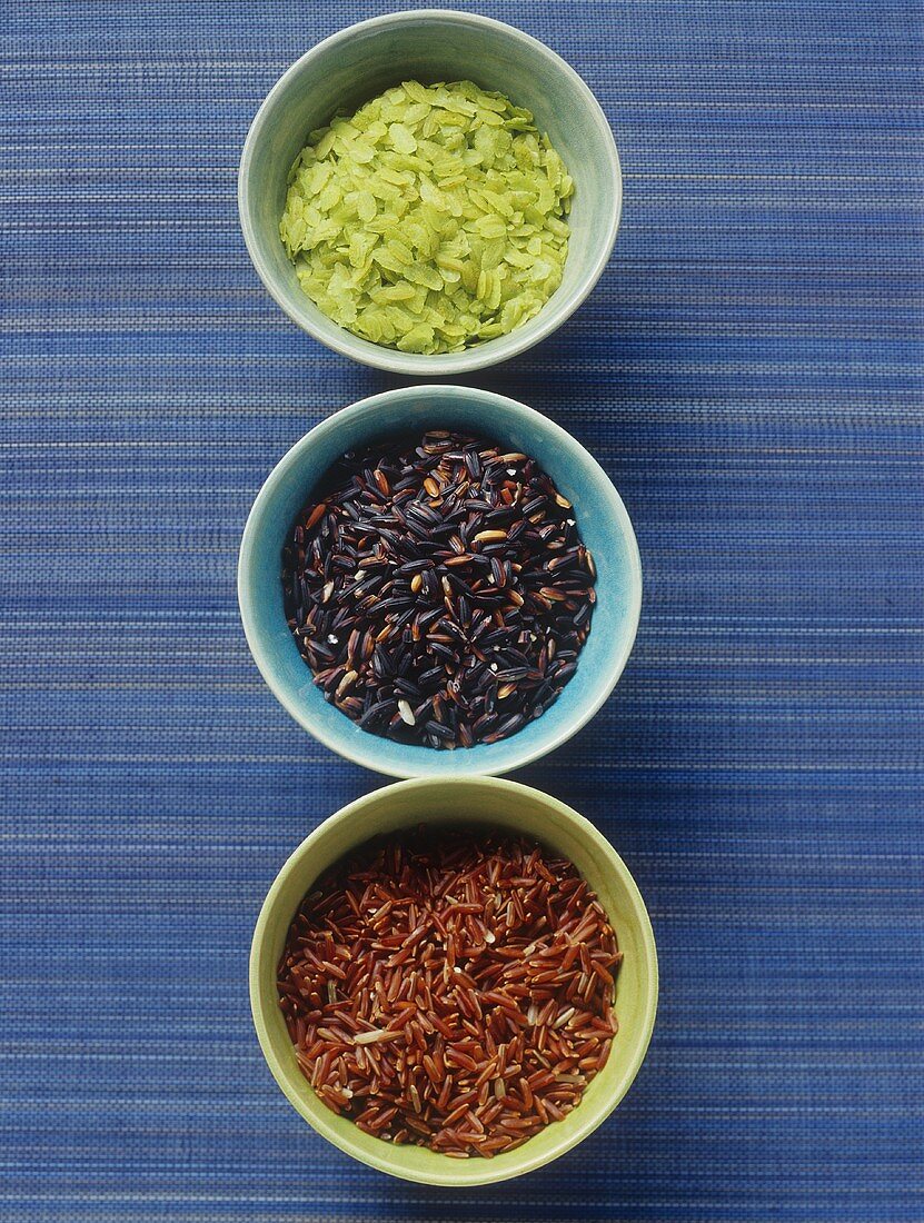 Red, green and black rice in small bowls