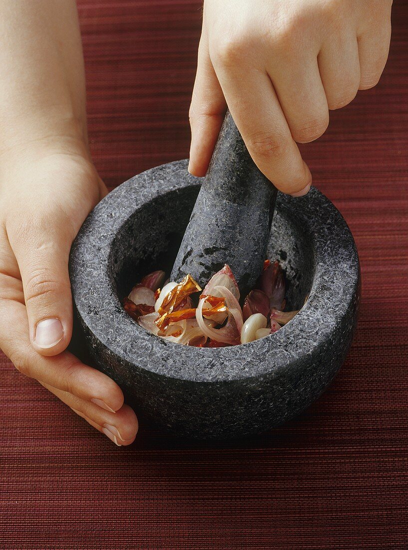 Crushing ingredients for curry paste in a stone mortar