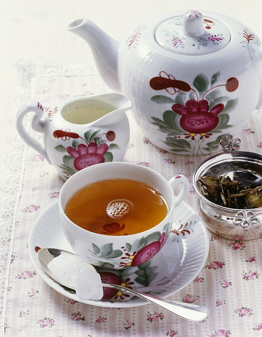 A cup of tea, teapot, cream jug
