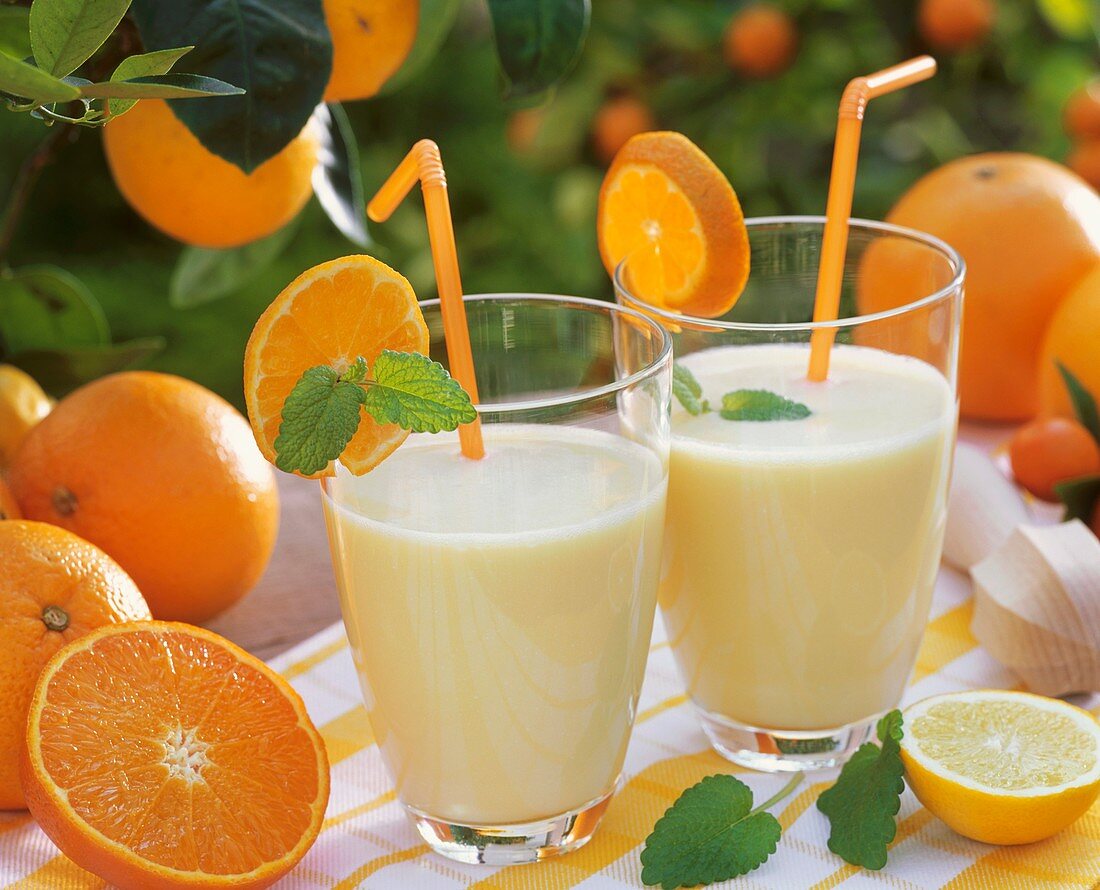 Zwei Gläser Orangenmilch mit Minze und Trinkhalmen im Freien