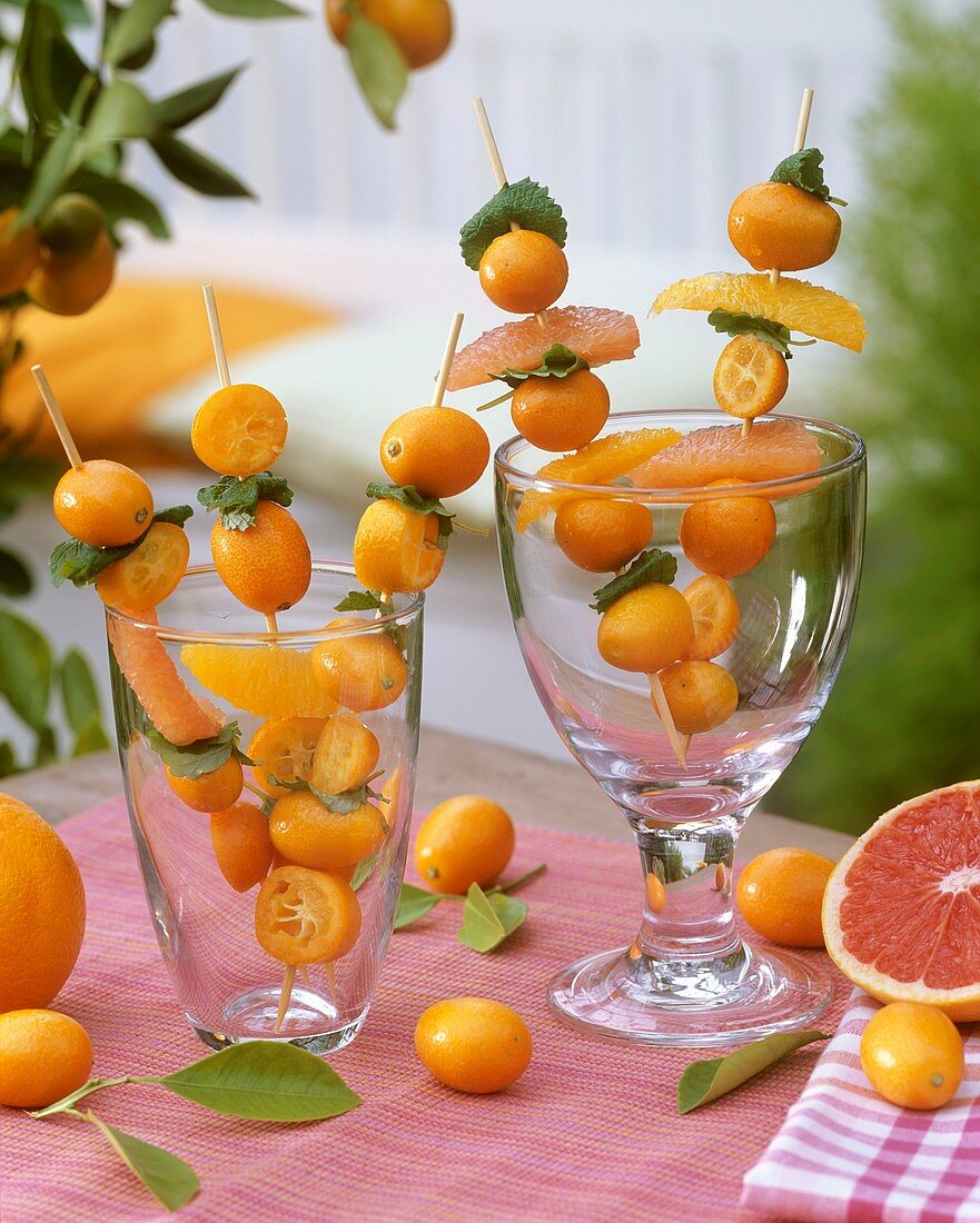 Kumquats, orange & grapefruit segments on skewers in glasses