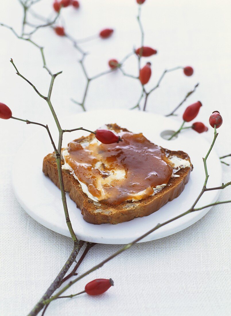 Rose hip and quince jam on bread, sprig of rose hips