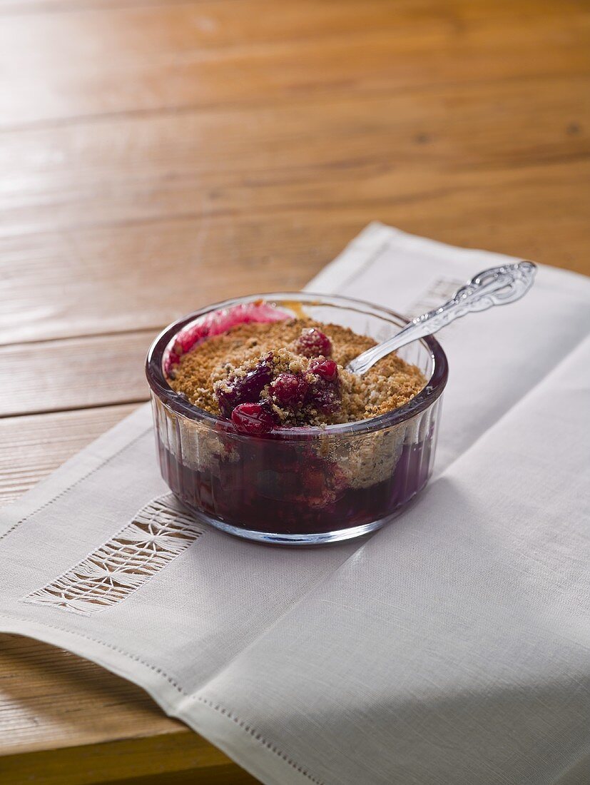 Cranberry crumble in a glass ramekin with a spoon