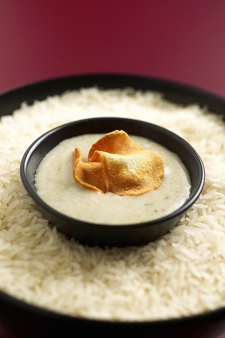 Topinambur-Cremesuppe, Topinambur-Chips in Schälchen auf Reis