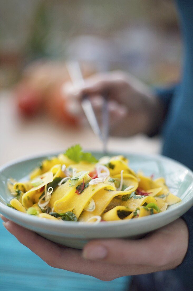 Woman holding dish of raw, marinated pumpkin salad in her hand