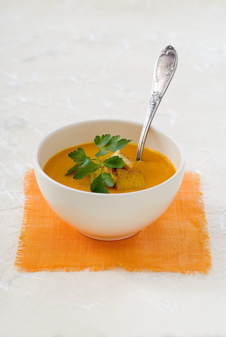 Pumpkin soup with croutons and parsley in a bowl