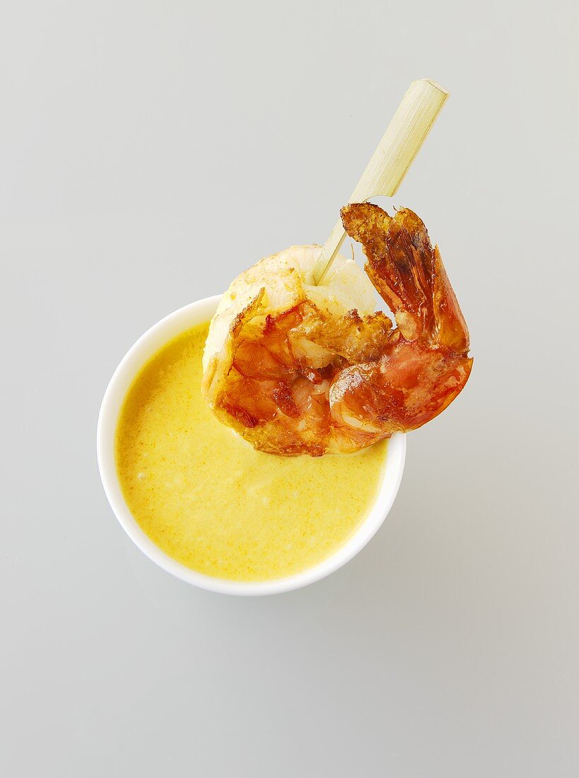 Fried prawn on a wooden skewer with coconut curry sauce