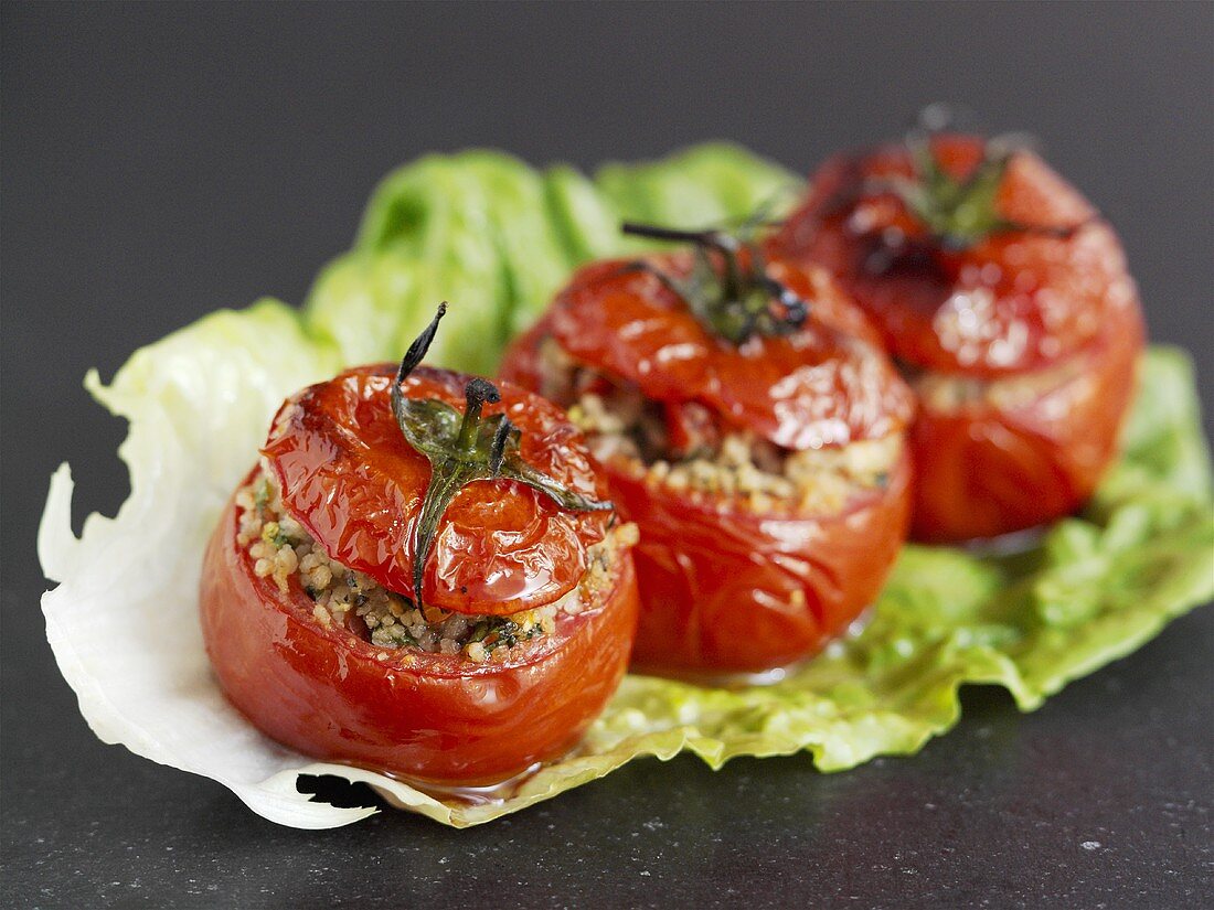 Mit Couscous gefüllte, gebackene Tomaten auf einem Salatblatt