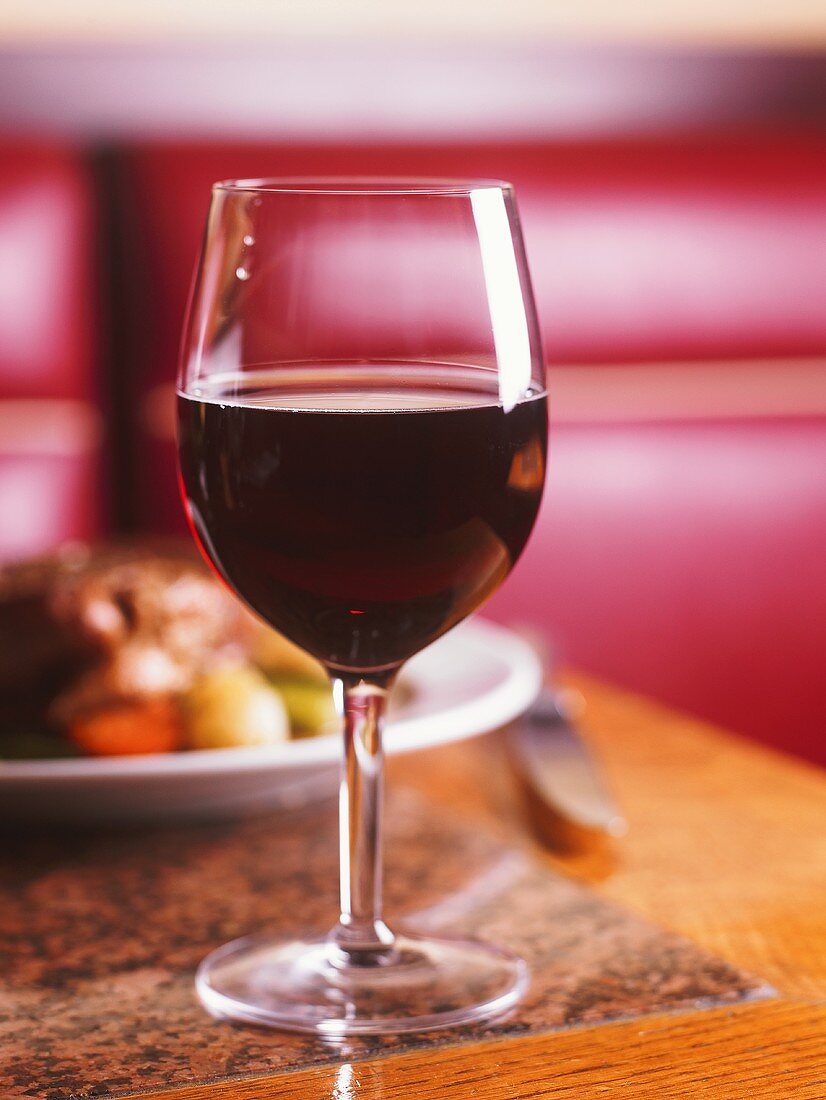Ein Glas Rotwein vor einem Gericht