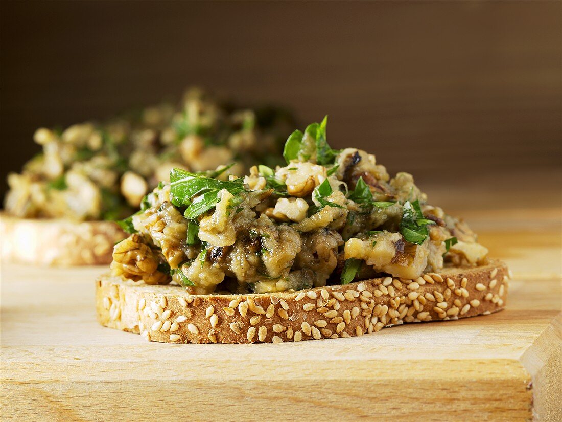 Geröstete Sesambrotscheiben, belegt mit Auberginen-Salat