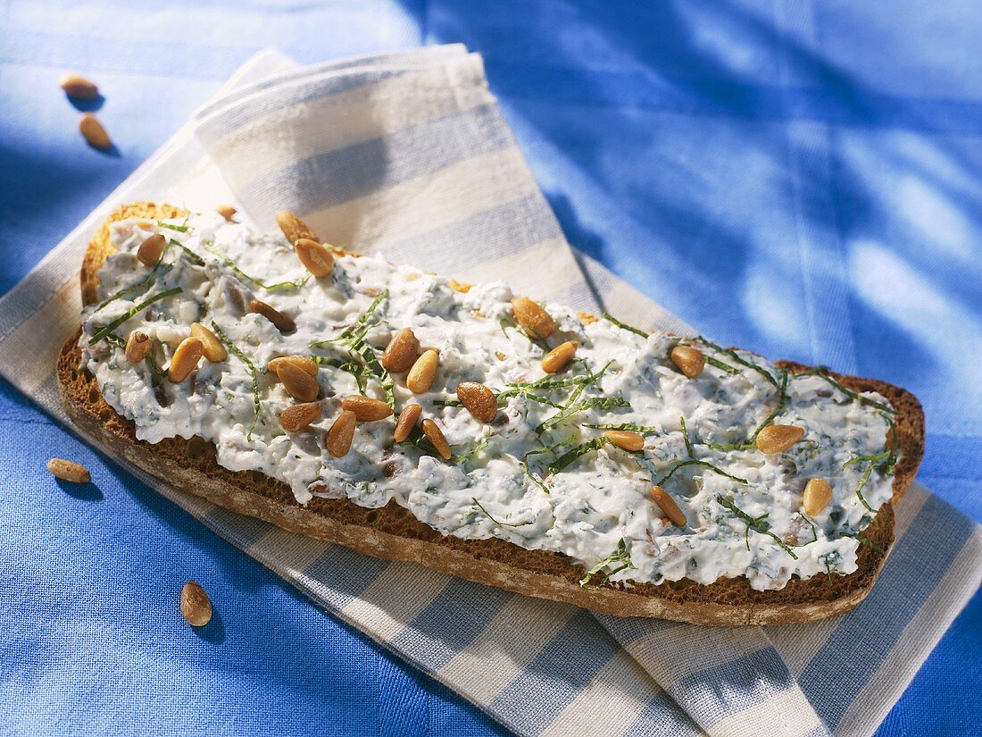 Soft cheese, pine nuts and mint on slice of toast