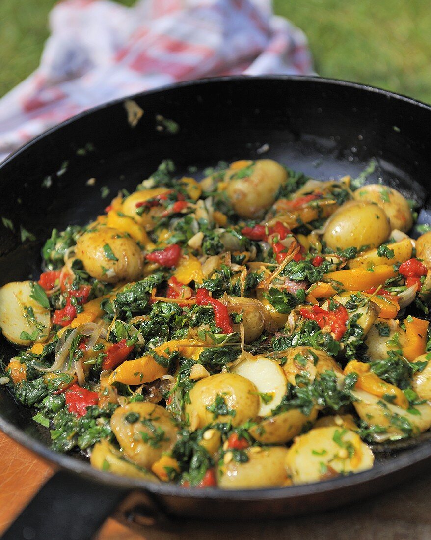 Potato tortilla with peppers and spinach in a frying pan