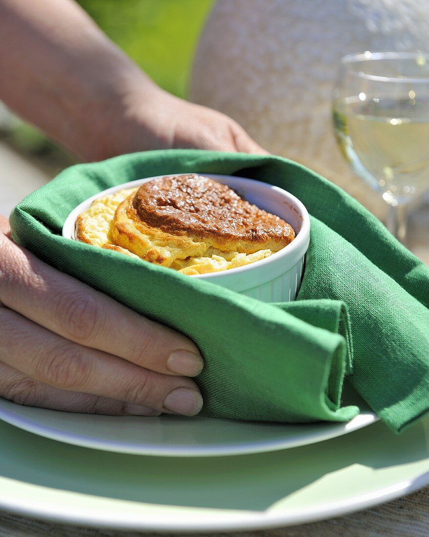Frau setzt Käsesoufflé mit einer Serviette auf ein Teller