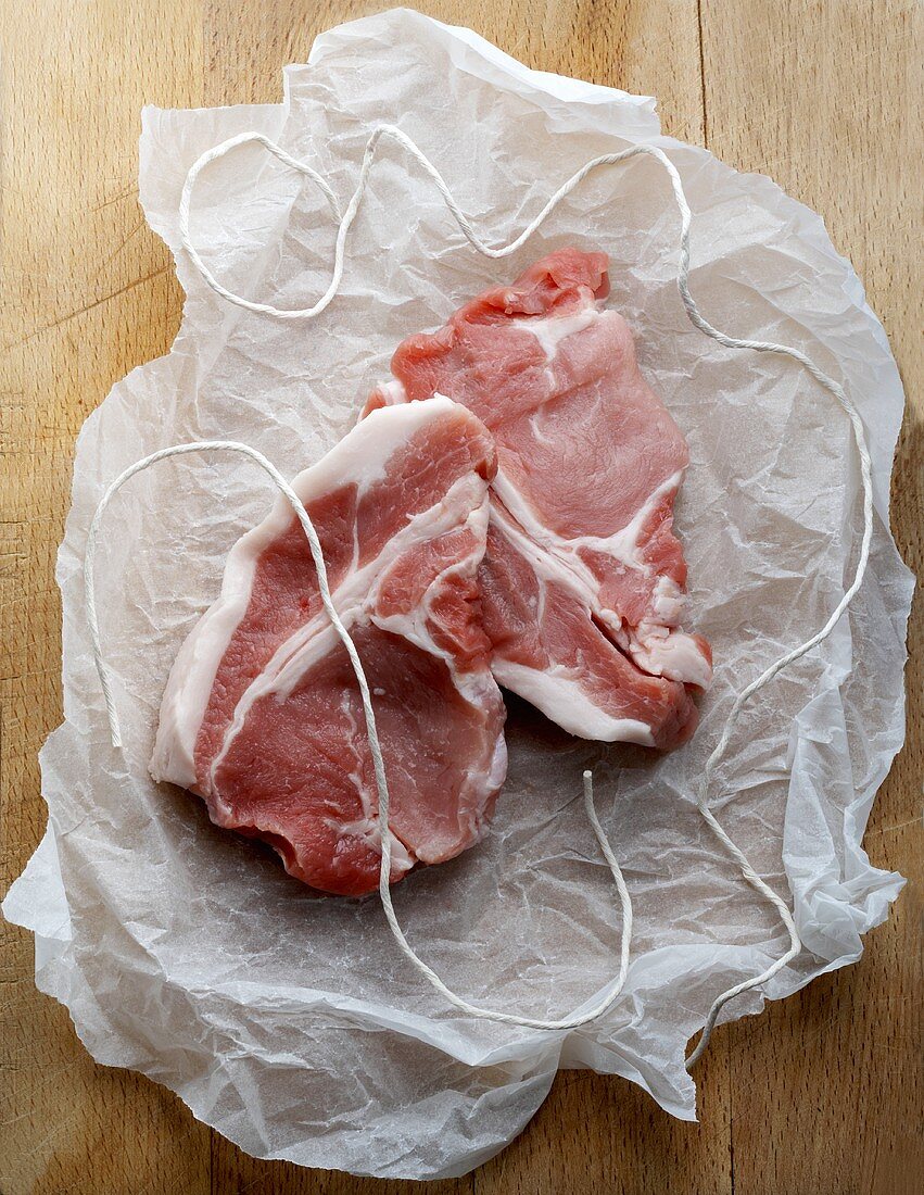 Two pork chops with kitchen string on paper