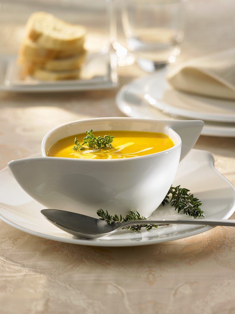 Pumpkin soup with sour cream and thyme in a soup cup