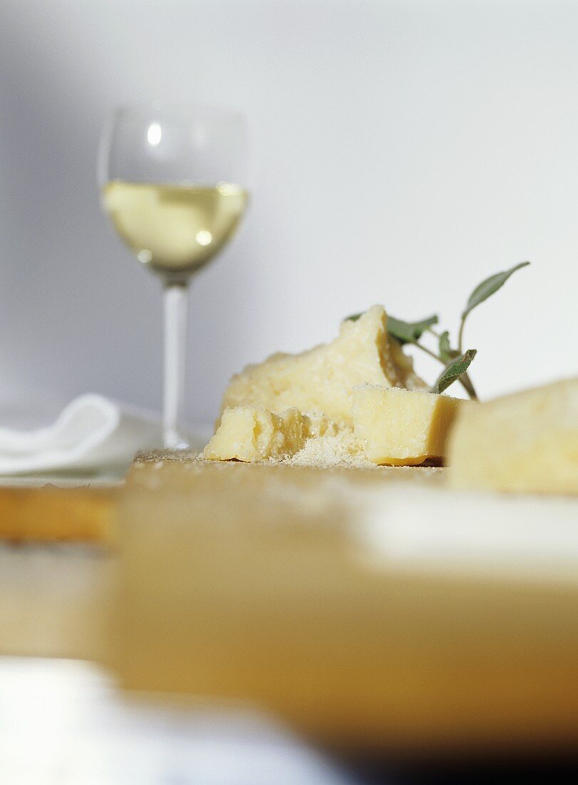 Pieces of Parmesan with sage and a glass of white wine