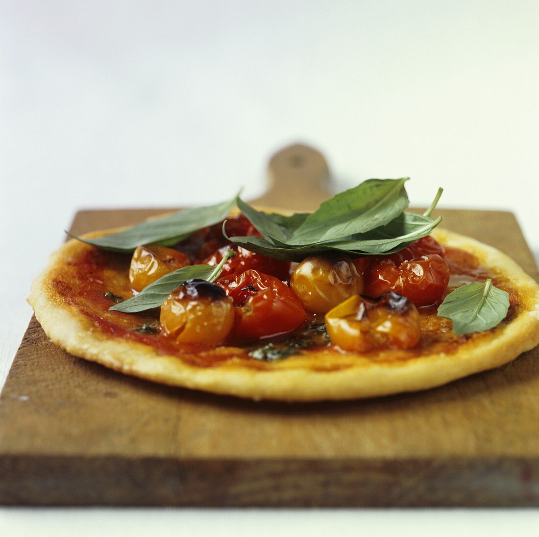 Tomaten-Pizza mit Basilikum auf einem Holzbrett